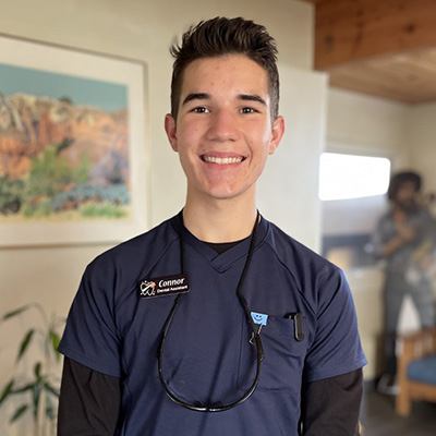 Young male dental professional in scrubs with stethoscope in modern office setting.