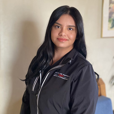 Professional woman in dark dental office uniform smiling at camera in clinical setting.